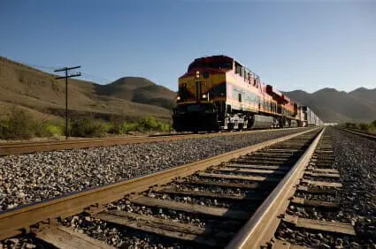Train locomotive engine carrying rail cars with empty track in foreground