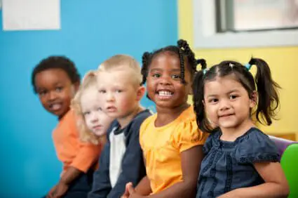Group of five young boys and girls sitting down and smiling