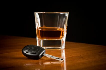 glass of liquor sitting next to car key