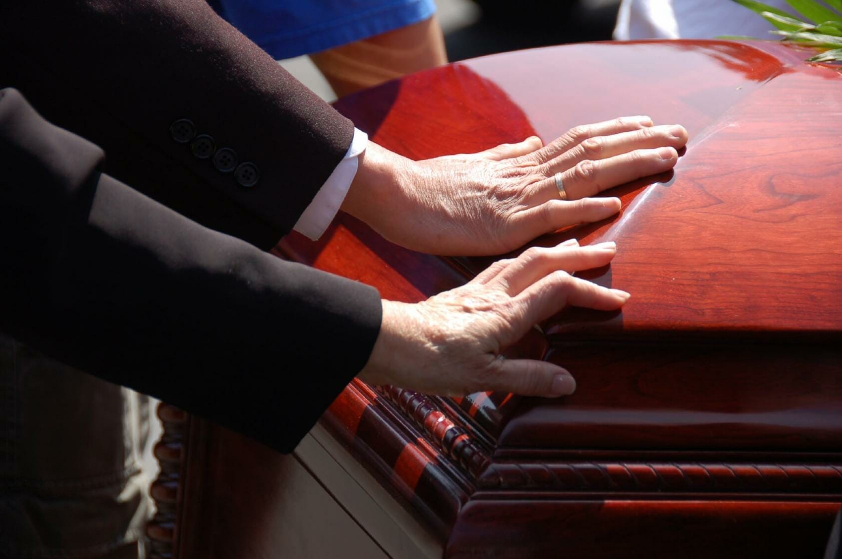 Two hands on funeral casket