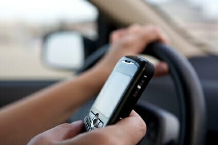 Close up view of a person operating a vehicle while using a phone