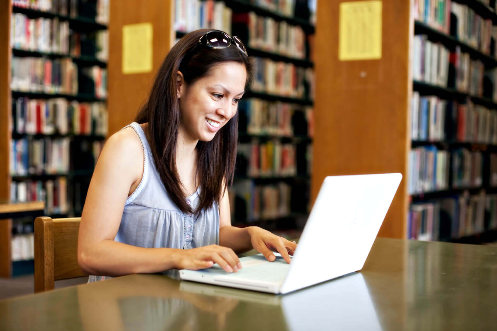 Woman smiling while using a laptop in a library