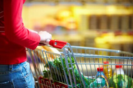 Woman grocery shopping holding shopping cart