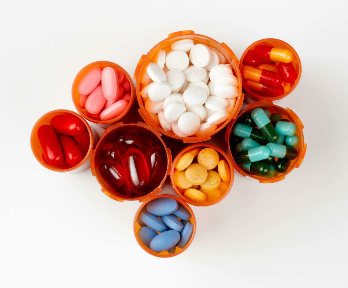 several prescription bottles filled with colorfu pills and capsules
