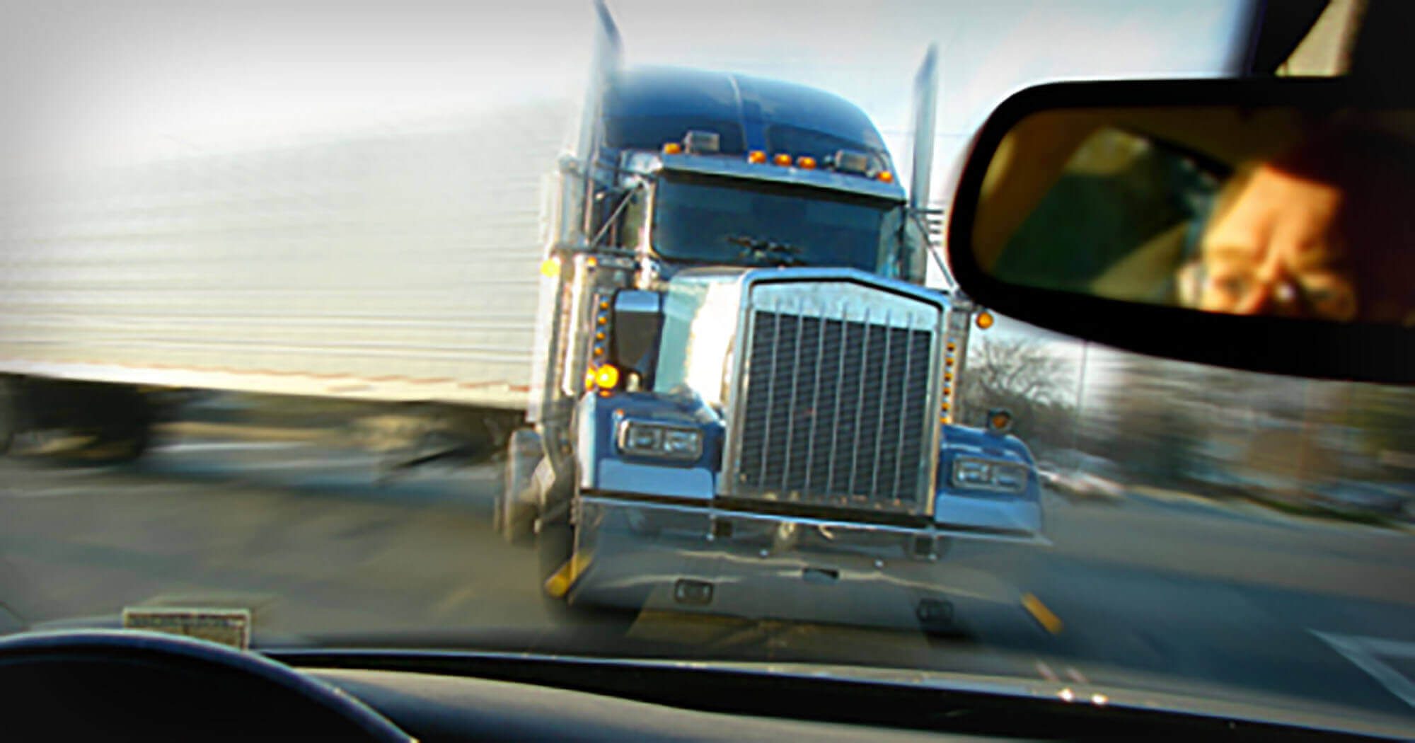 semi-truck driving toward man in car at intersection
