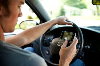 Man driving a car while using a cell phone with one hand.