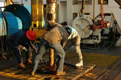 Oil workers operating oil drilling equipment