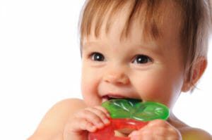 Toddler smiling and teething on a toy