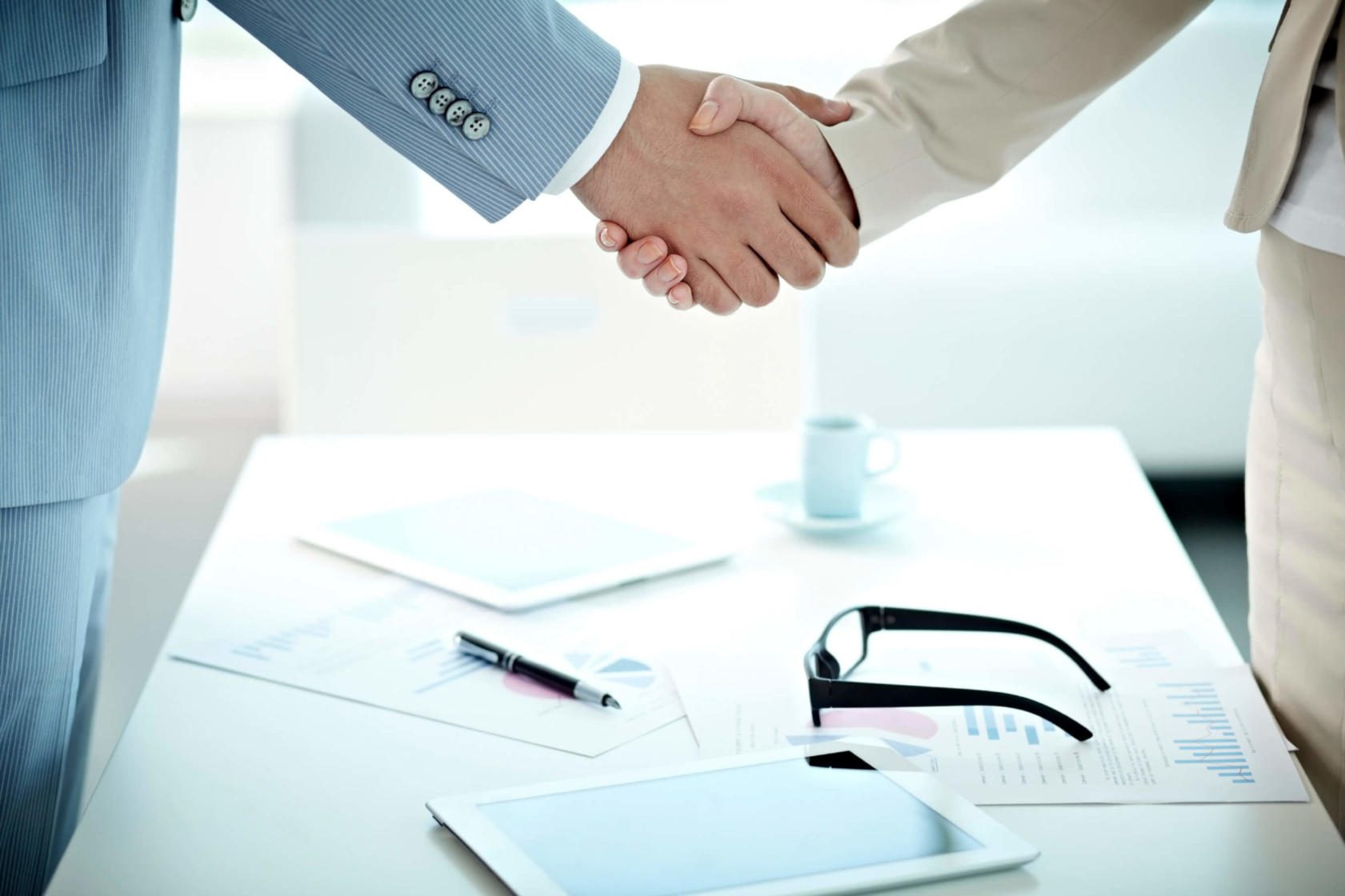 Person shaking hands with another person at a desk.