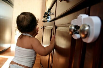 Baby resting on childproofed wooden kitchen cabinets