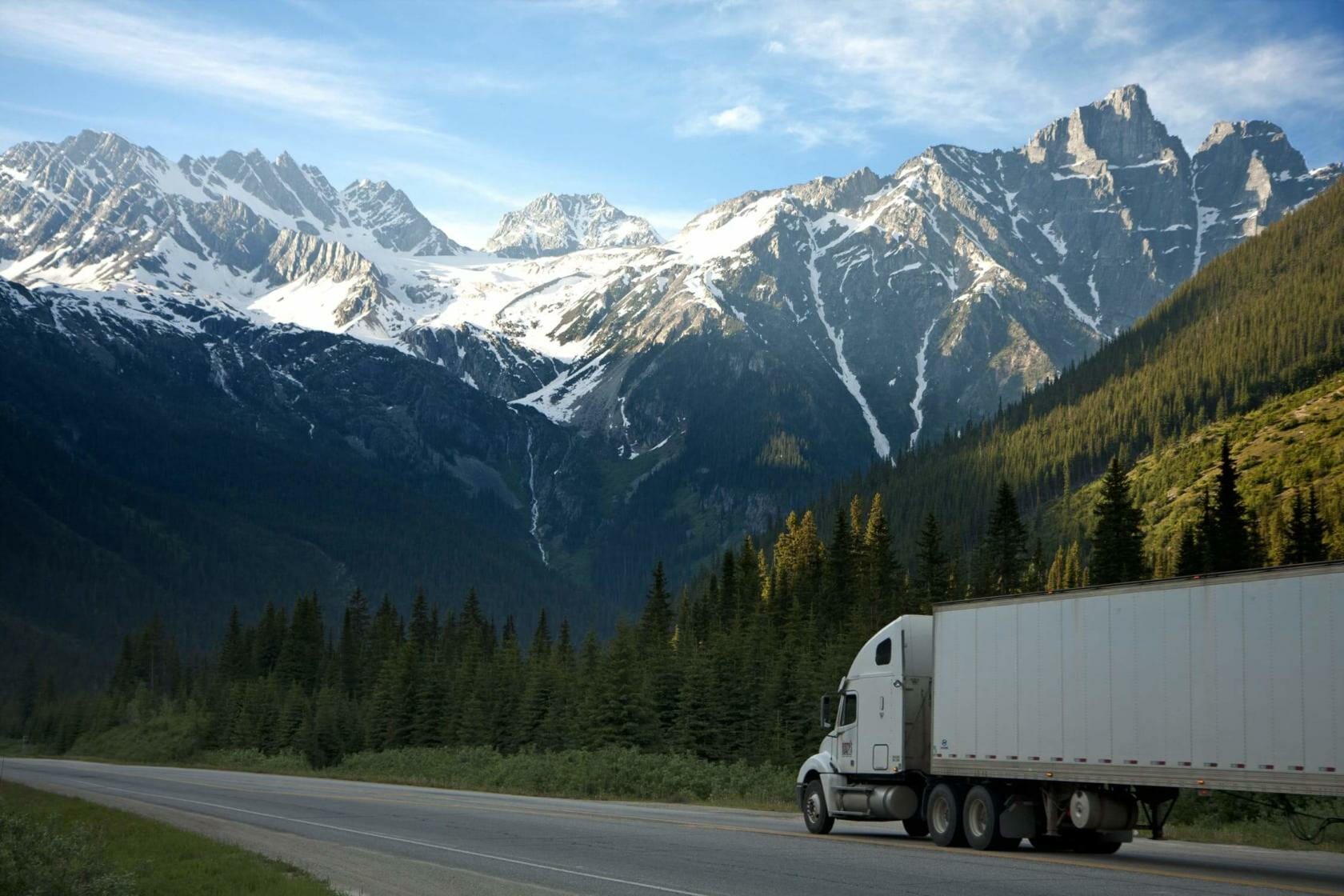 18-wheeler traveling with mountain and forests in background