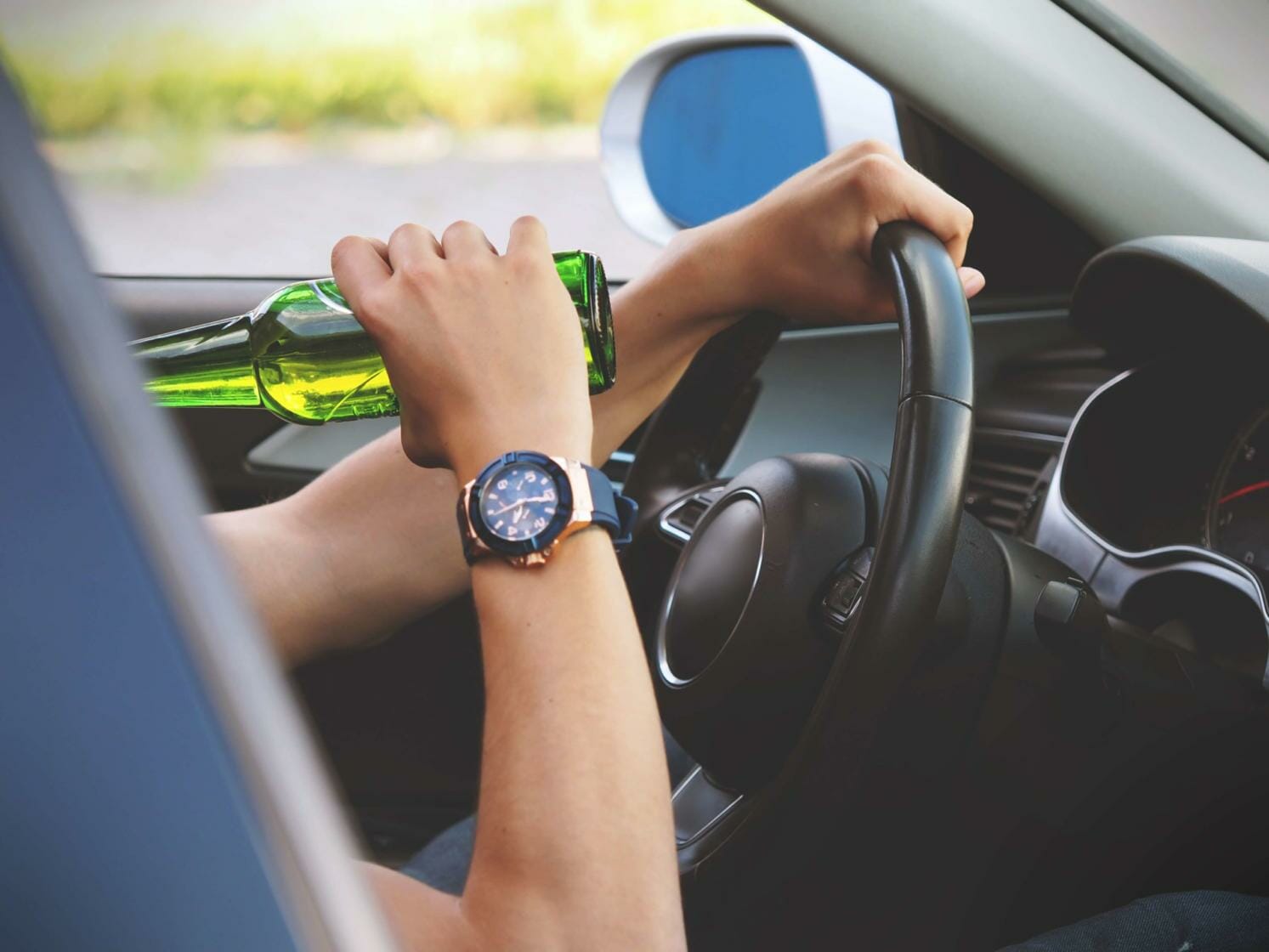 Man sipping a bottle of beer while driving