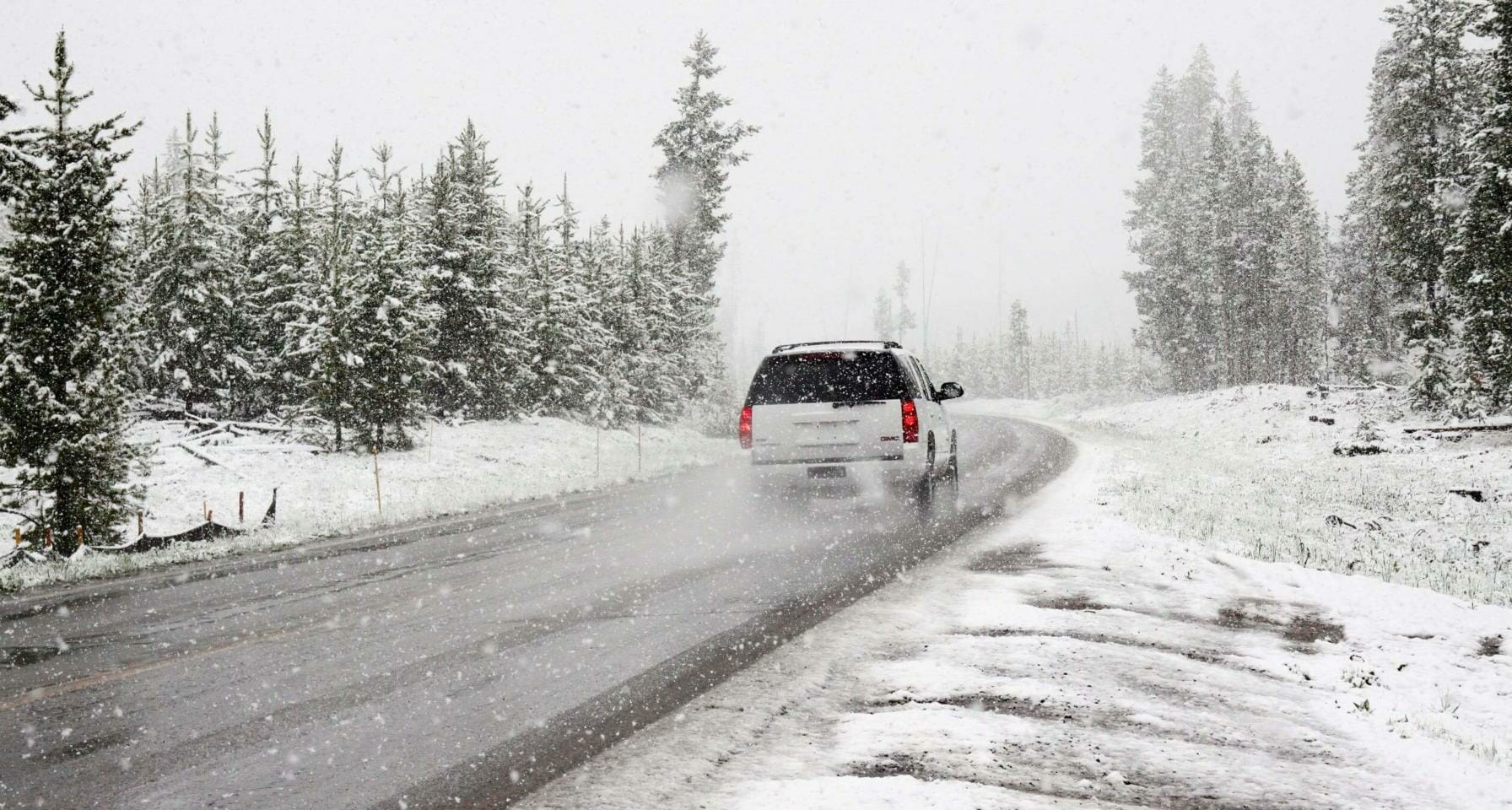 SUV traveling across frozen road in snowy terrain