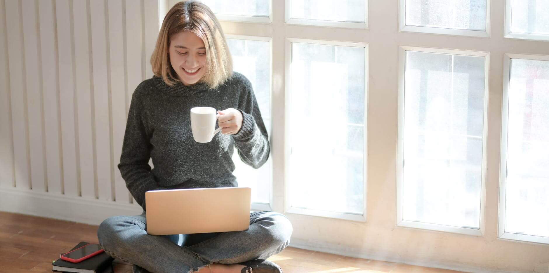 Young woman with cup of coffee on laptop