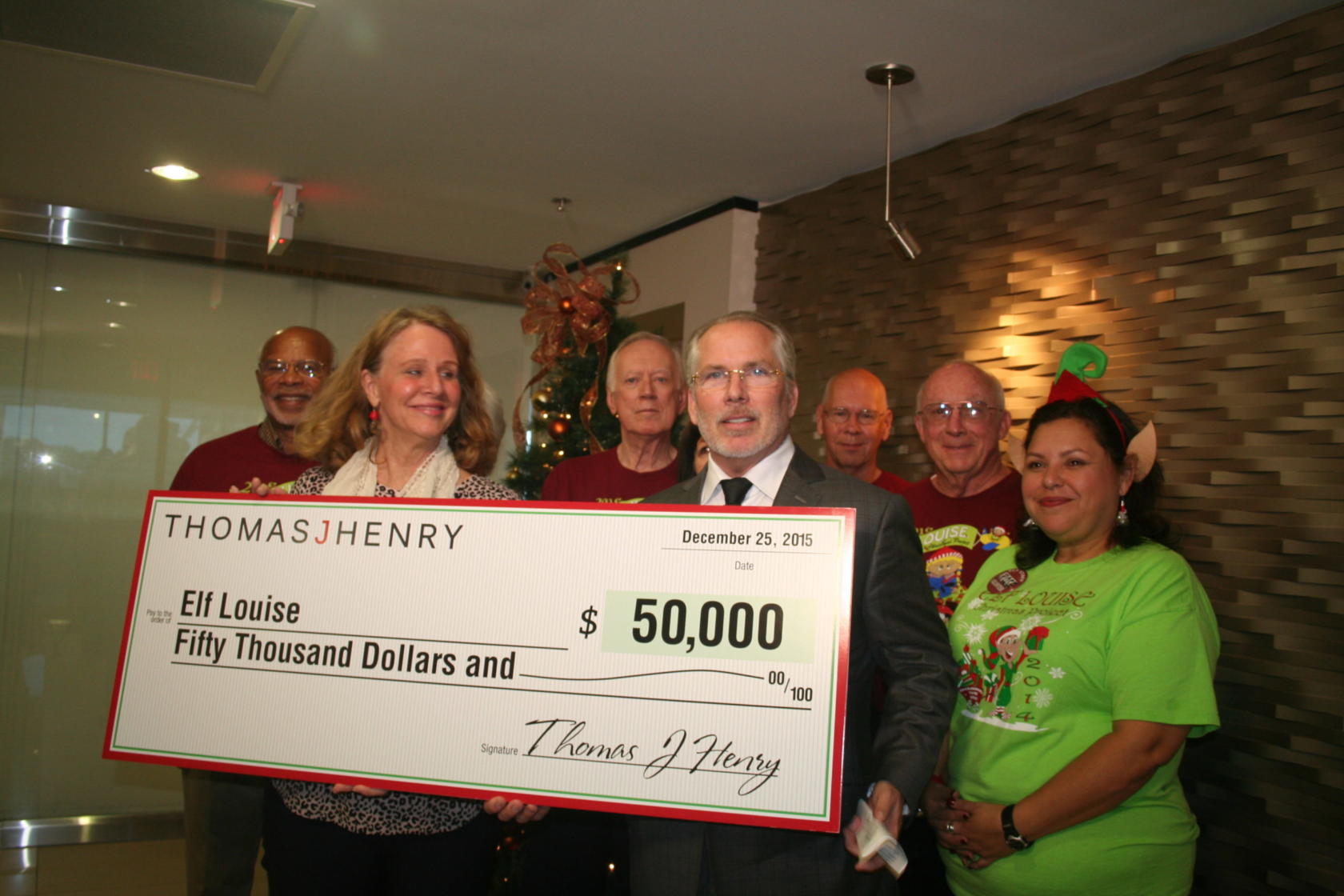 Thomas J .Henry holding a large check for $50,000 for Elf Louise
